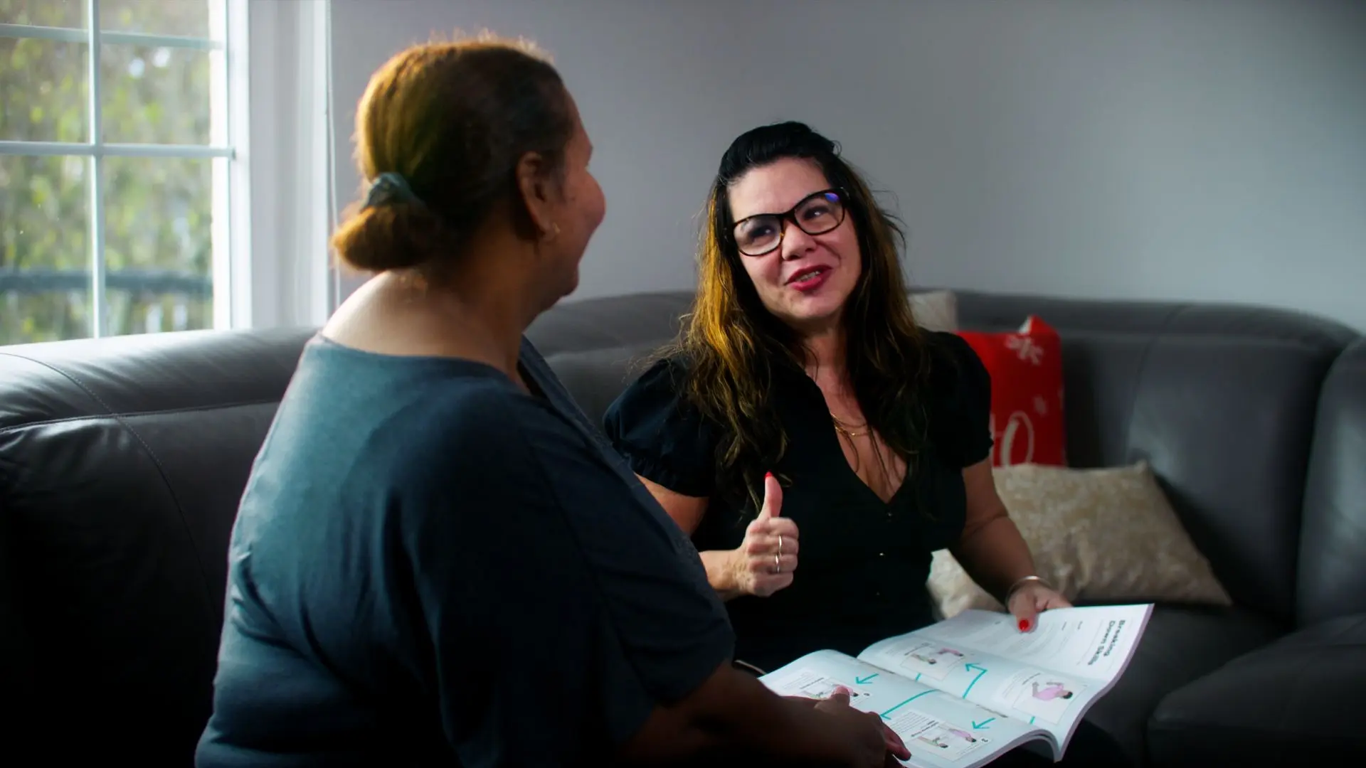 ABA therapist providing guidance to a parent during a home-based session, reviewing strategies for behavior support.